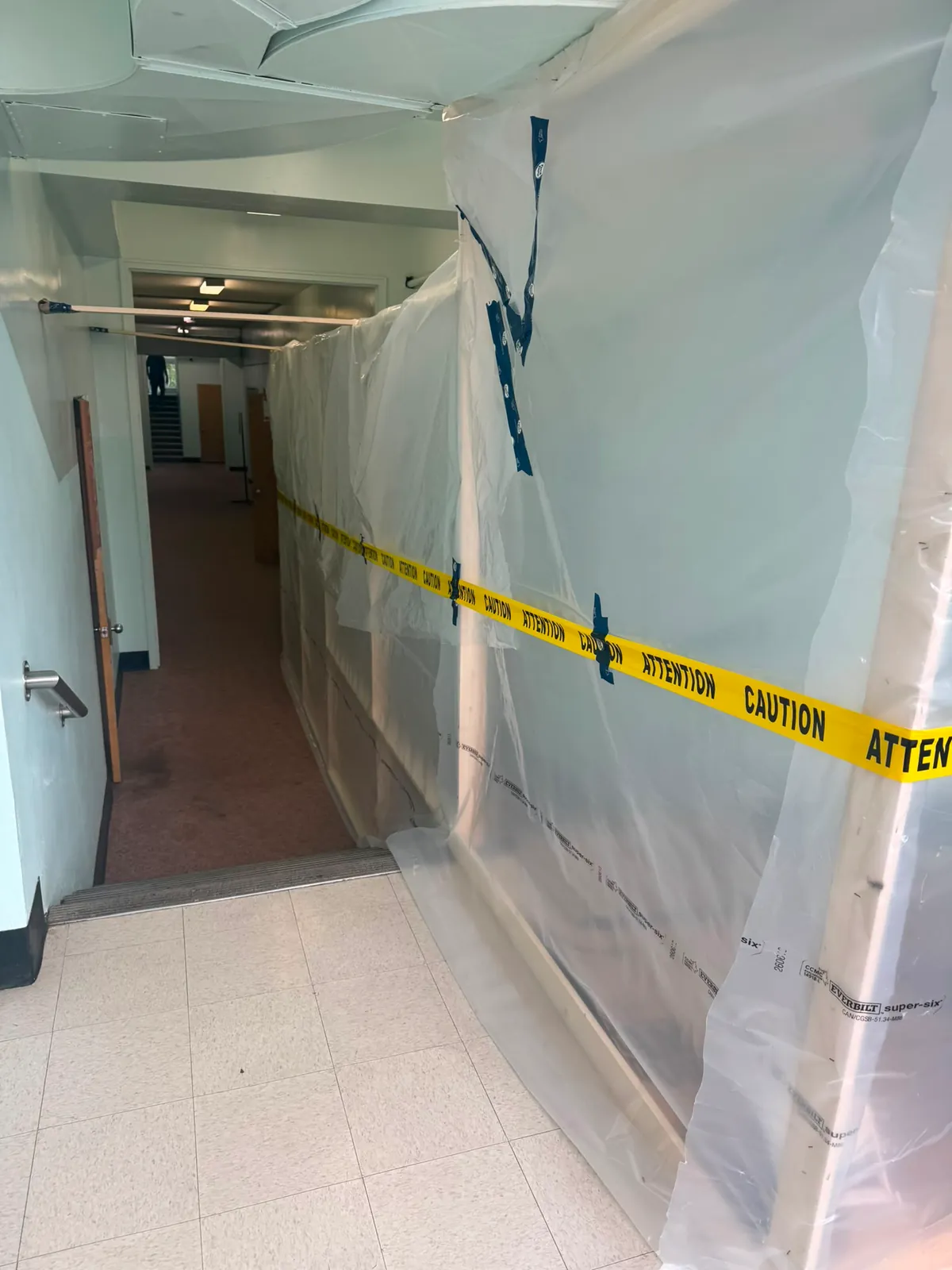 Long corridor with plastic containment walls and caution tape along one side
