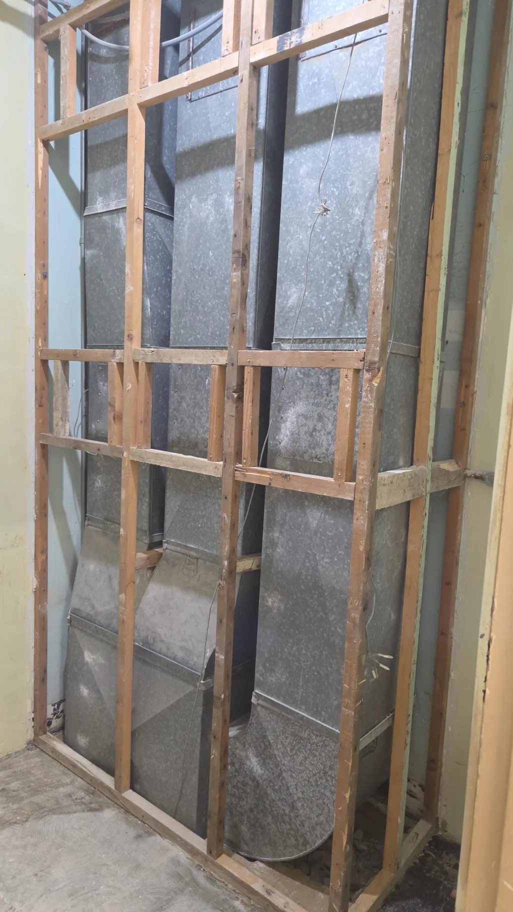 New wood-framed wall with metal ductwork showing between the studs