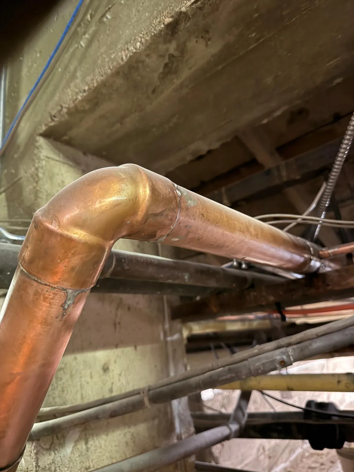 New copper supply line with a soldered elbow running beneath the floor structure
