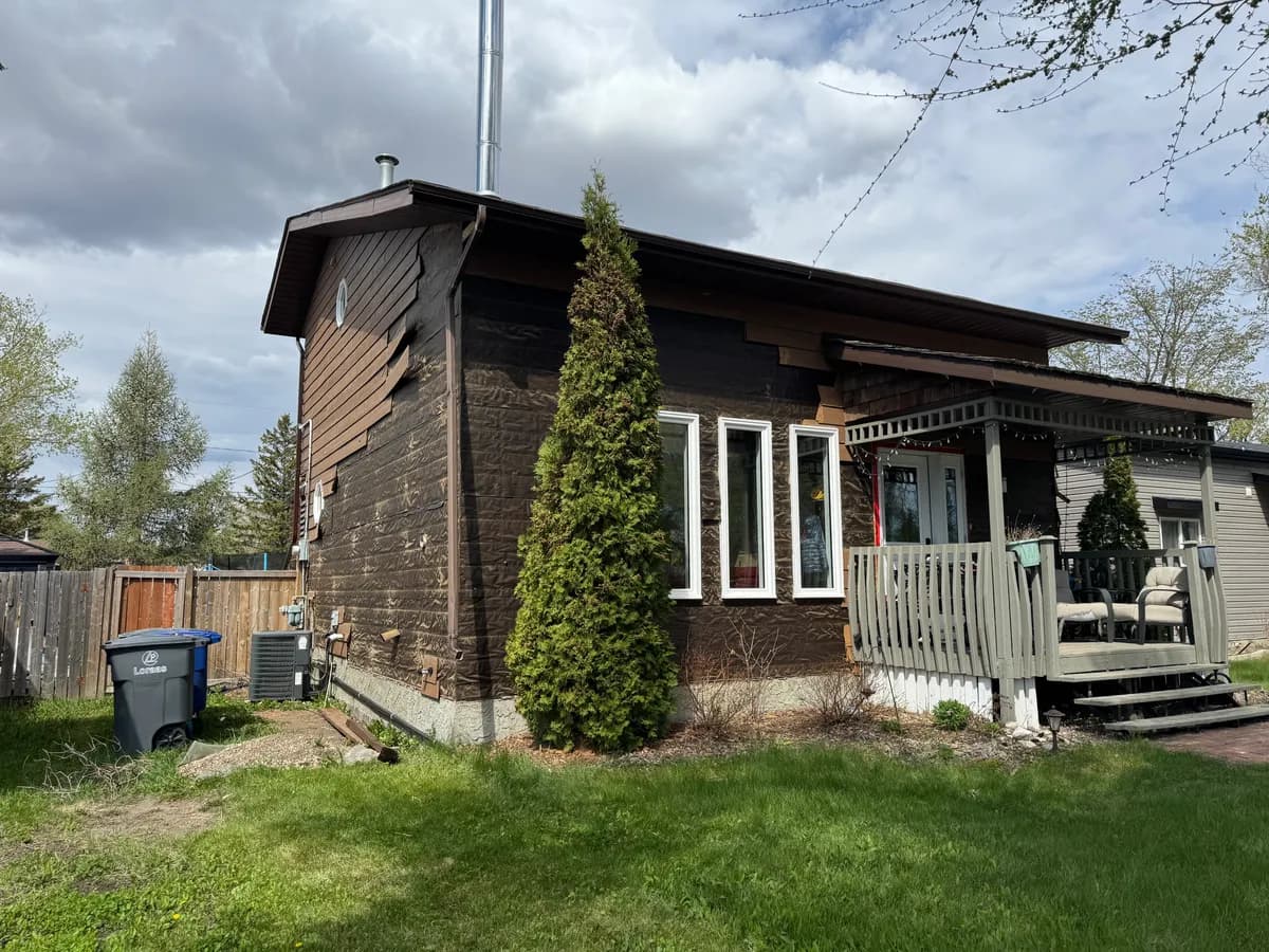 Front corner of a house during the work, with loose and damaged boards on the upper gable siding
