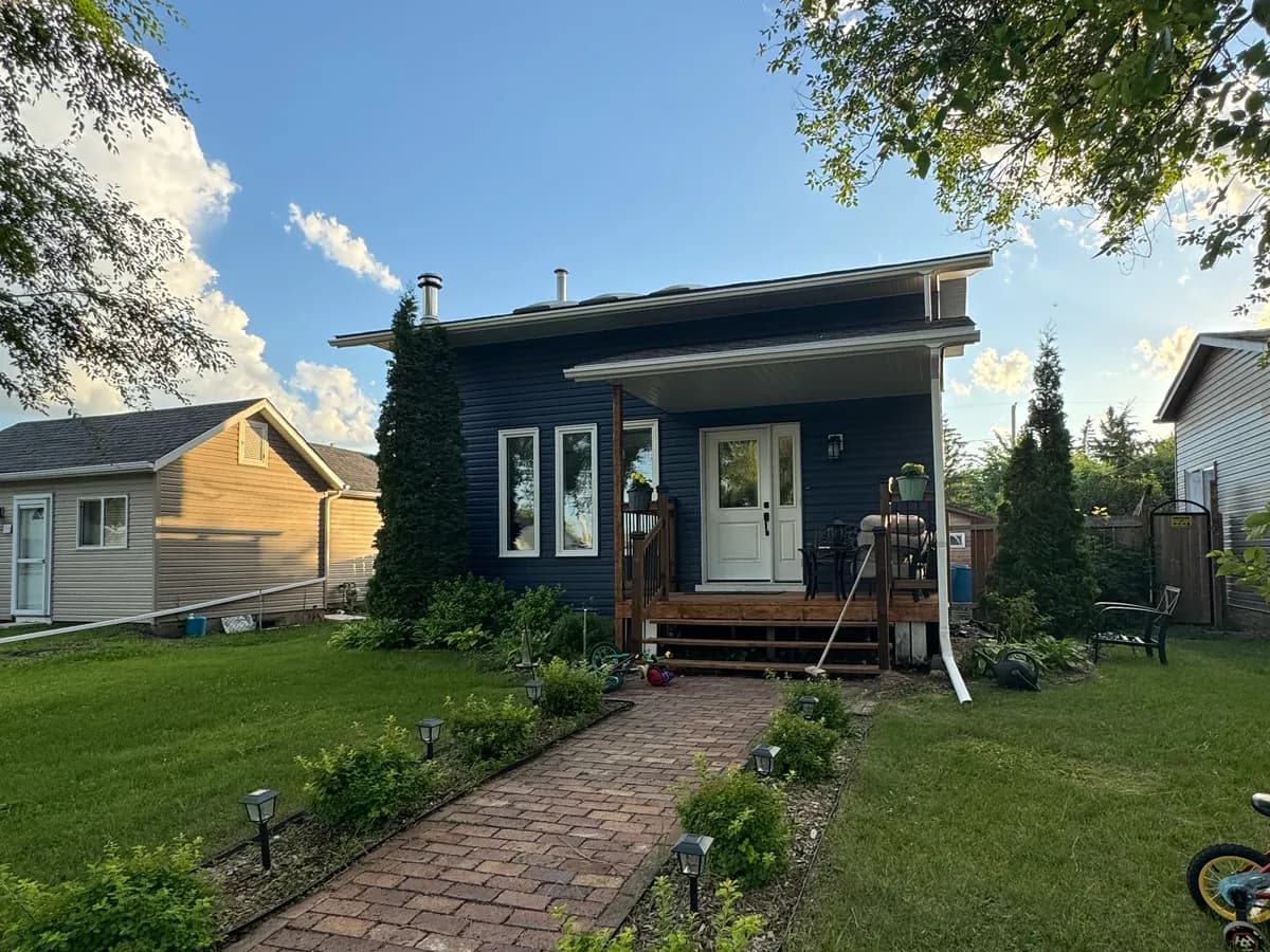The same house after the siding replacement, with navy vinyl siding, white trim and a stained porch